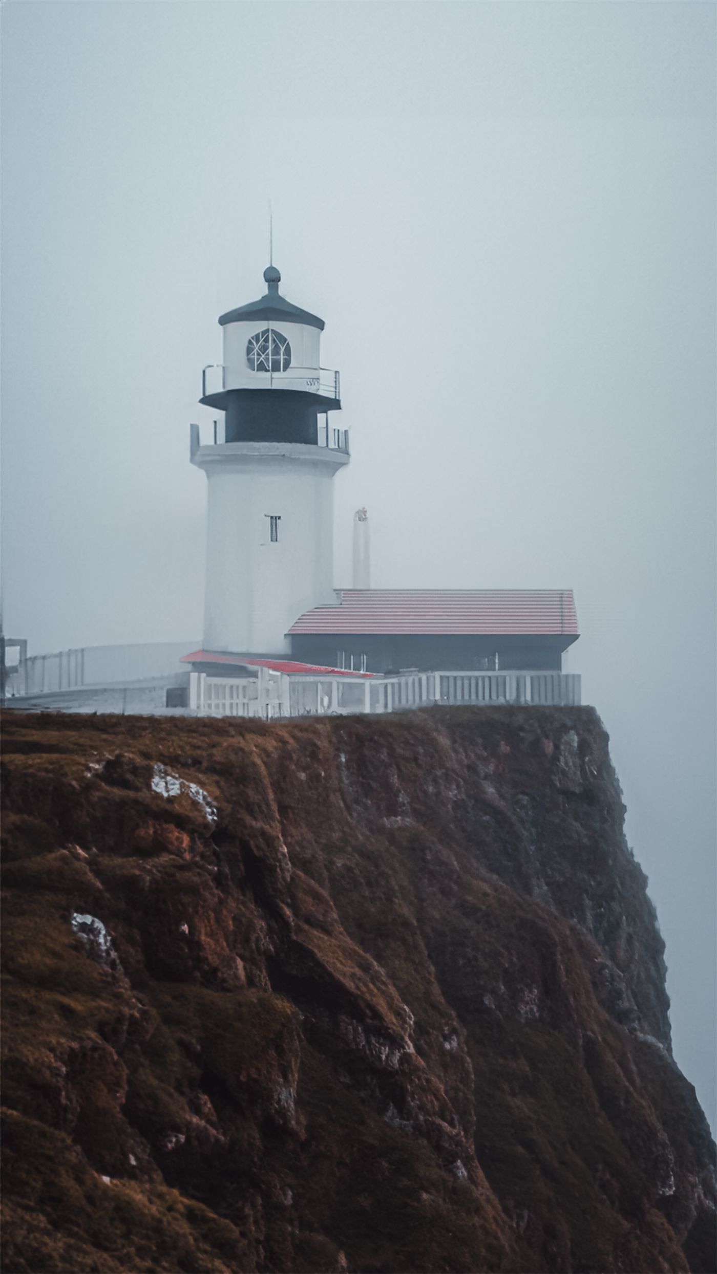 Lighthouse on a rocky coast in mist