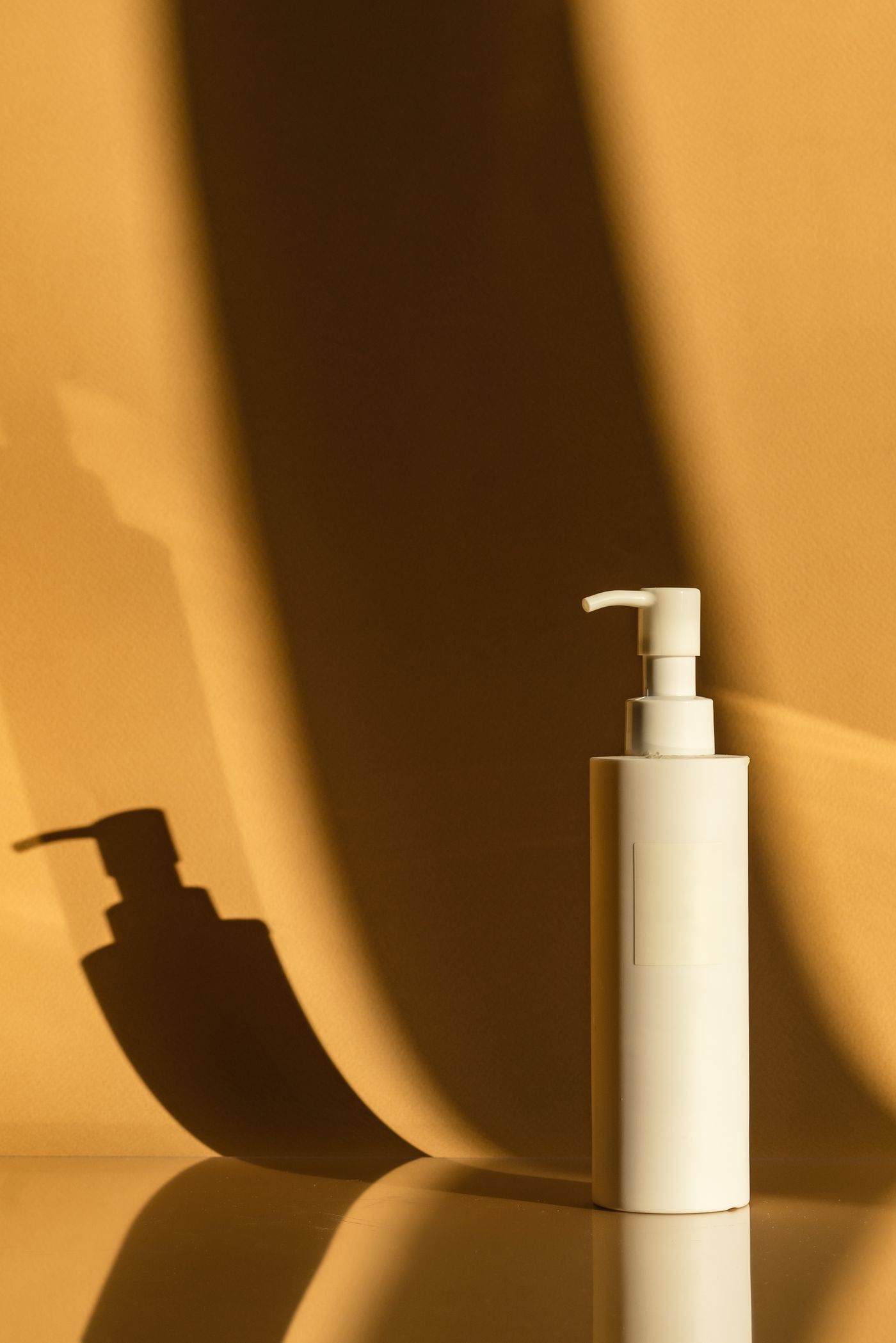 Minimal cosmetic pump bottle on a beige background