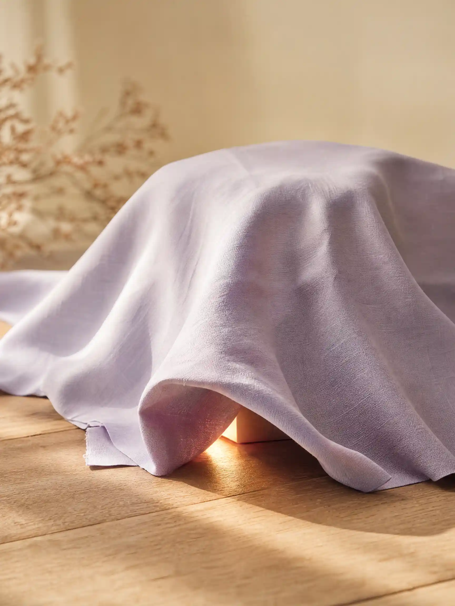 Sneak peek video hero frame with a lilac cloth hiding a glowing product